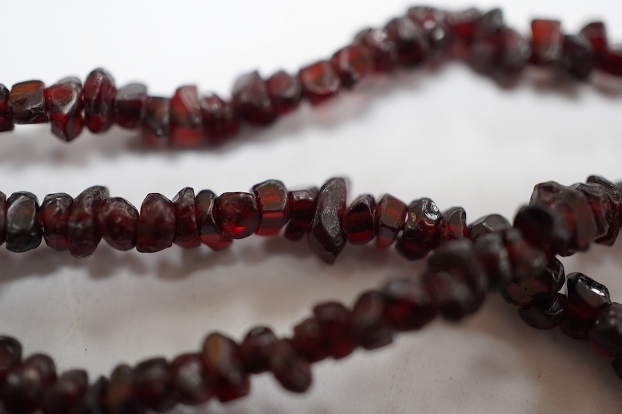 A late 19th/early 20th century multi strand rough cut garnet set necklace, with a yellow metal mounted oval cameo shell clasp, 43cm. Condition - poor to fair